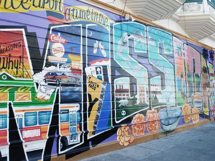 Colorful mural on outside of building using various images to spell out the word "Mission"